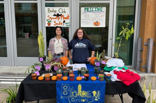Students at a Table with plants and other items for sale