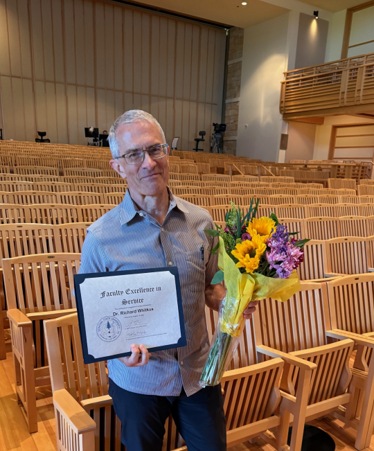 Dr. Richard Whitkus with flowers and award